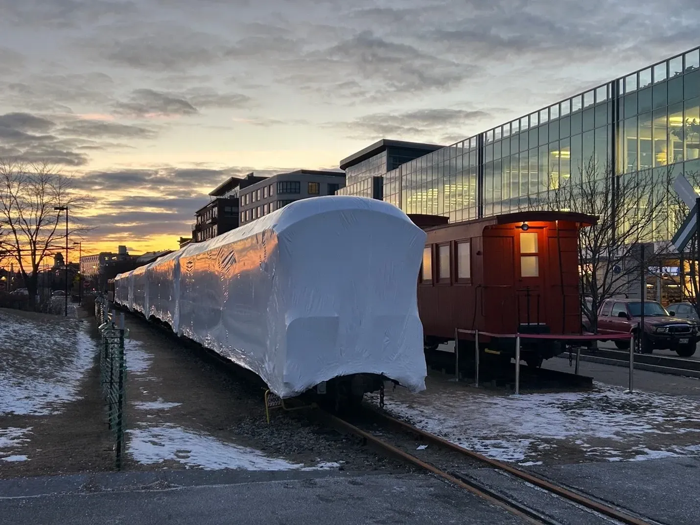 A train car is wrapped in plastic and is on the tracks.
