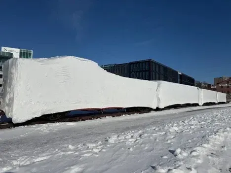 A train covered in snow is going down the tracks.