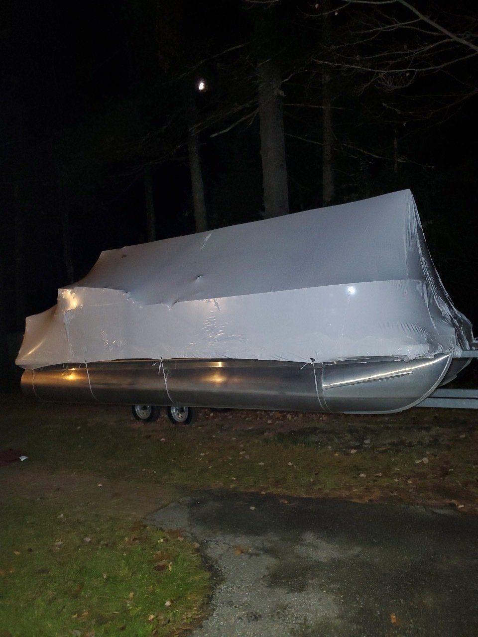 A boat is wrapped in plastic and sitting on top of a trailer.