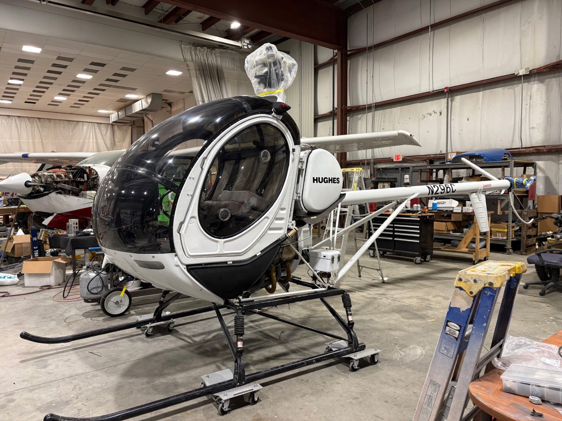 Helicopter in a hangar. Black and white, single-person aircraft with open cockpit, skids, and tail rotor.
