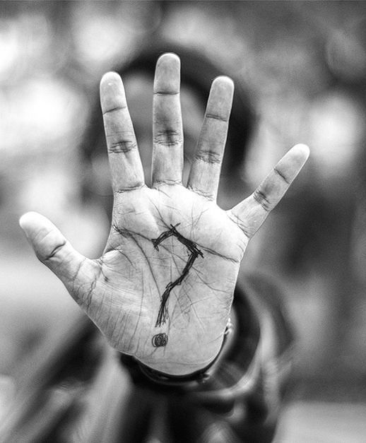 A black and white photo of a person covering their face with their hand.