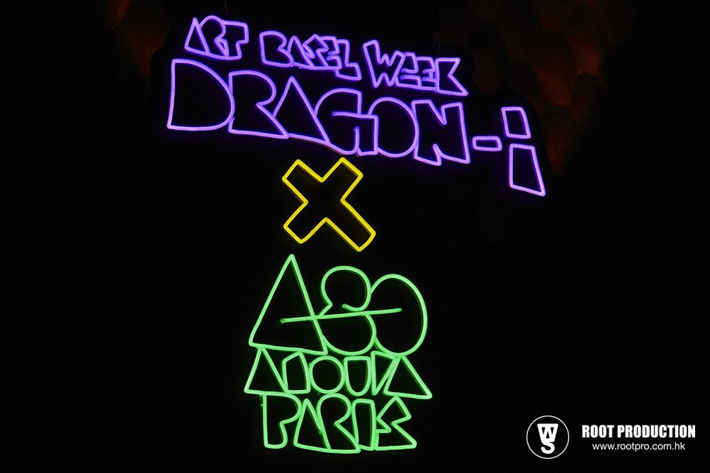 Neon sign: Art Basel Week Dragon-i X 430 Anna Paris, purple and green letters on black.