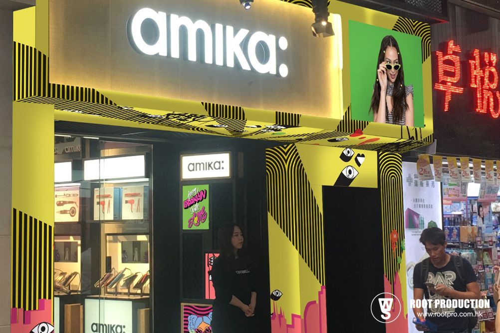 An Amika beauty store entrance, yellow and black design, with a person standing by the entrance.