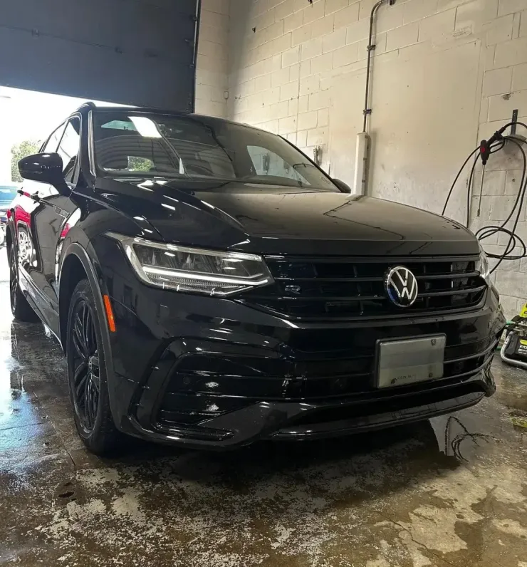 A black Volkswagen Tiguan parked inside a garage with wet floors.