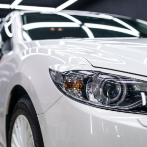 A close-up, angled view of the front passenger side of a clean, shiny white sedan parked in an indoor garage.