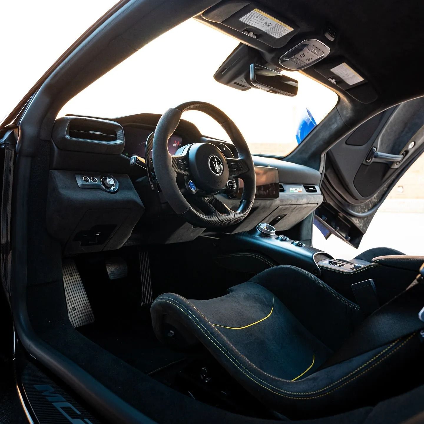 Interior view of a sleek, dark-toned luxury sports car with bucket seats and a leather-wrapped steering wheel.