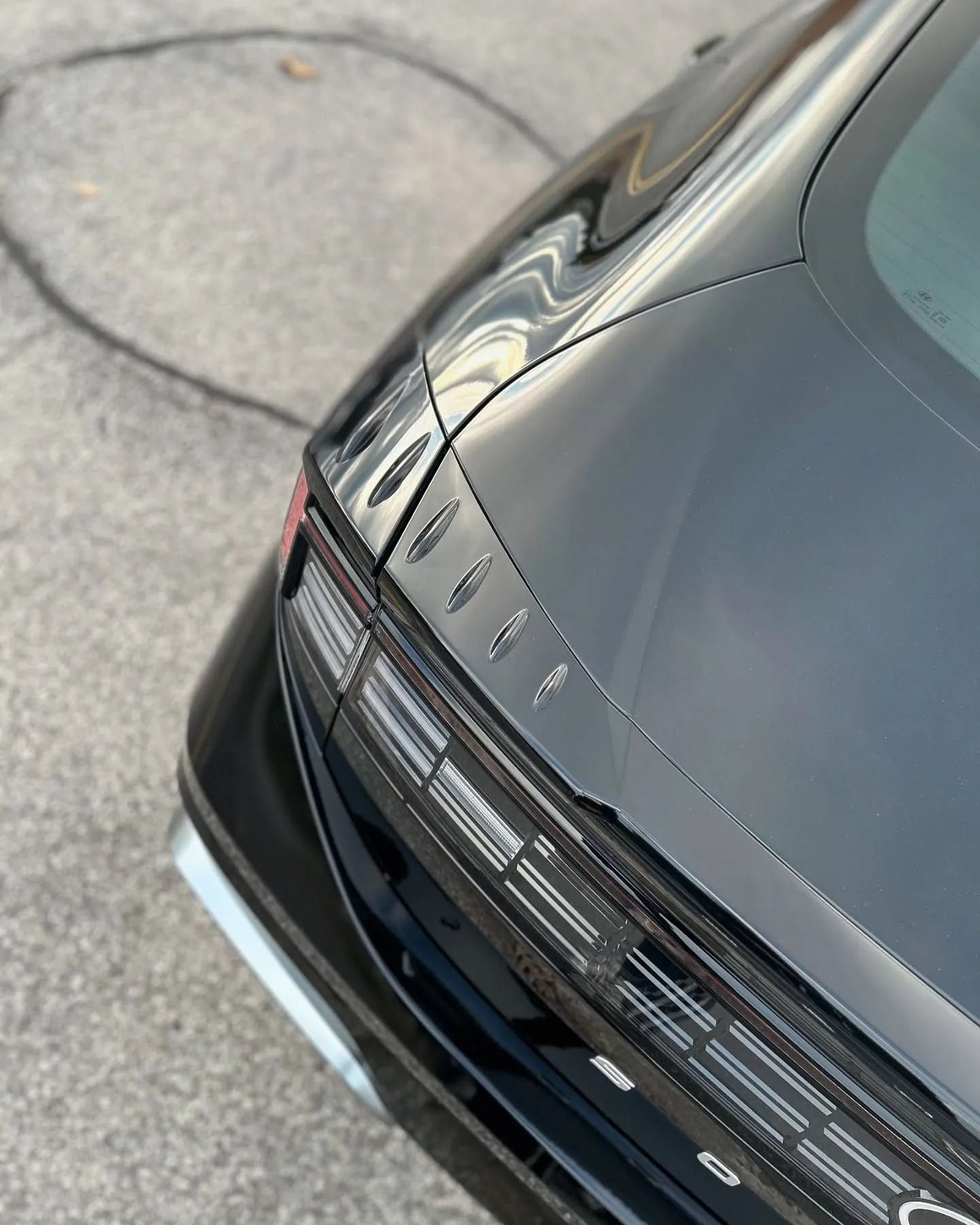 A close-up of the rear corner of a black Hyundai Ioniq 6 showing the parametric pixel taillights and trunk lid.