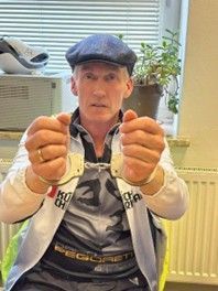 Unser Tandemfahrer Jörg sitzt traurig auf einem Stuhl und hält seine gefesselte Hände nach vorne um zu zeigen wie arm er dran ist.