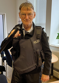 Manfred mit Polizeiweste an. Er setzt ein richtiges bad cop Gesicht.
