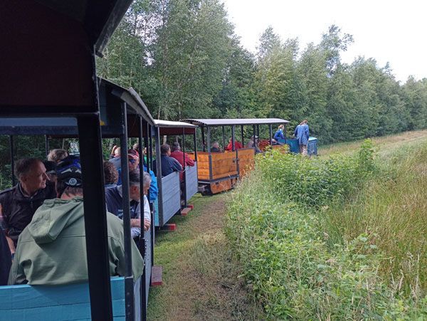 Foto von der Lorenbahn. Man sieht eine kleine Lokomotive mit dahinter drei offenen Wagen, in denen Mitglieder der Weissen Speiche sitzen.
