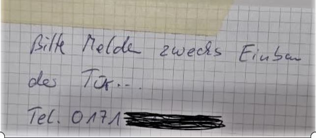Foto von dem Zettel mit dem Text: Bitte melden zwecks Einbau der Tür, und dann einen Telefonnummer