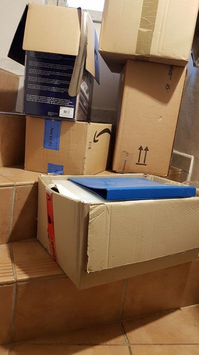 Foto von einer Chaotischen Ansammlung von Umzugskartons und sonstigen Kartons unterschiedlicher Größe. Alles steht irgendwie, aber man hat das Gefühl, dass der Stapel umfällt, wenn eine Fliege sich auf einen Karton setzt.