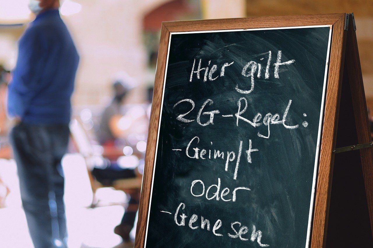 Tafel, auf dem mit weißer Kreide geschrieben ist: Hier gilt 2G-Regel: Geimpft oder Genesen