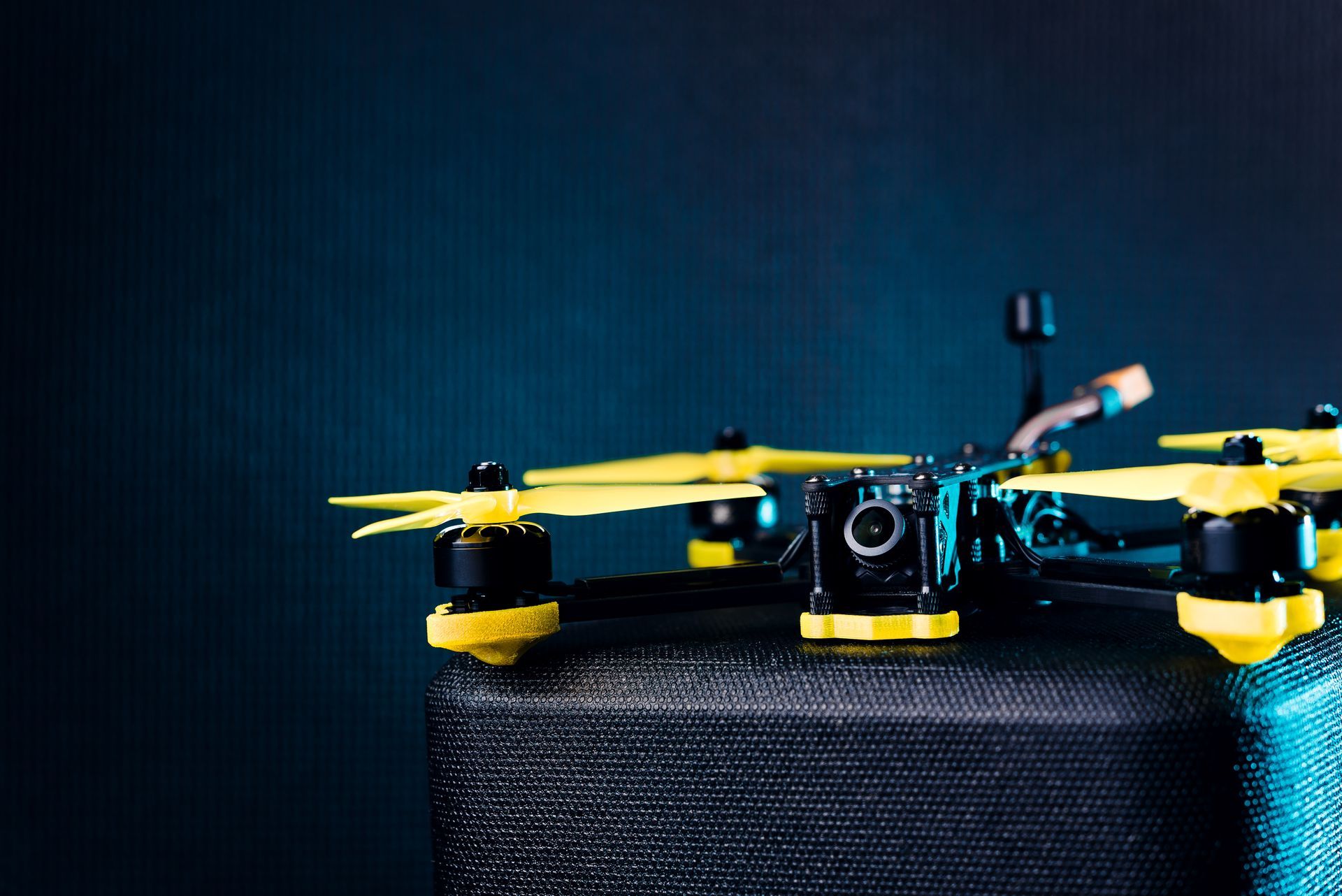 A yellow and black drone is sitting on top of a black box.