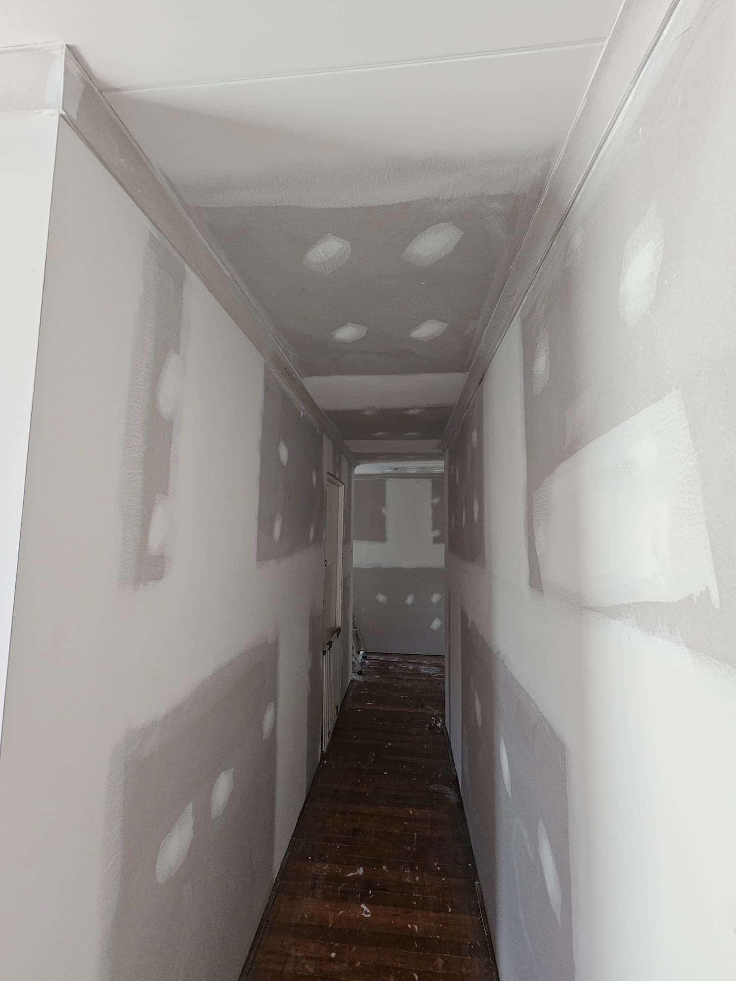 A Long Hallway With Drywall on the Walls and a Wooden Floor — Poljak Plasterers in Kirwan, QLD