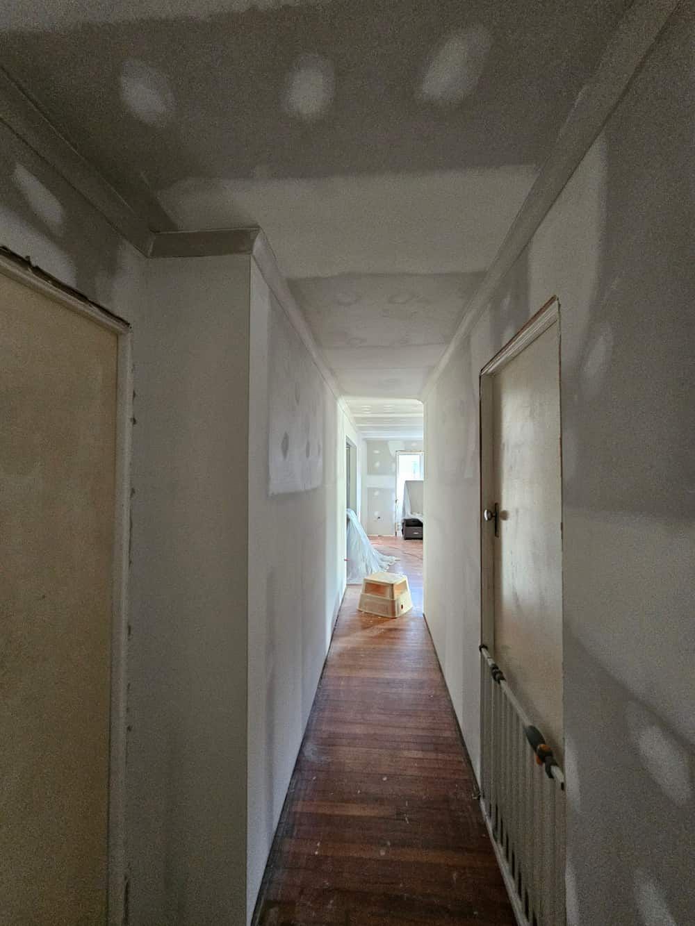 A Long Hallway With a Wooden Floor and White Walls — Poljak Plasterers in Oonoonba, QLD