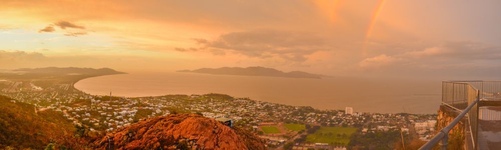An Aerial View of a City at Sunset With a Rainbow in the Sky — Poljak Plasterers in Belgian Gardens, QLD