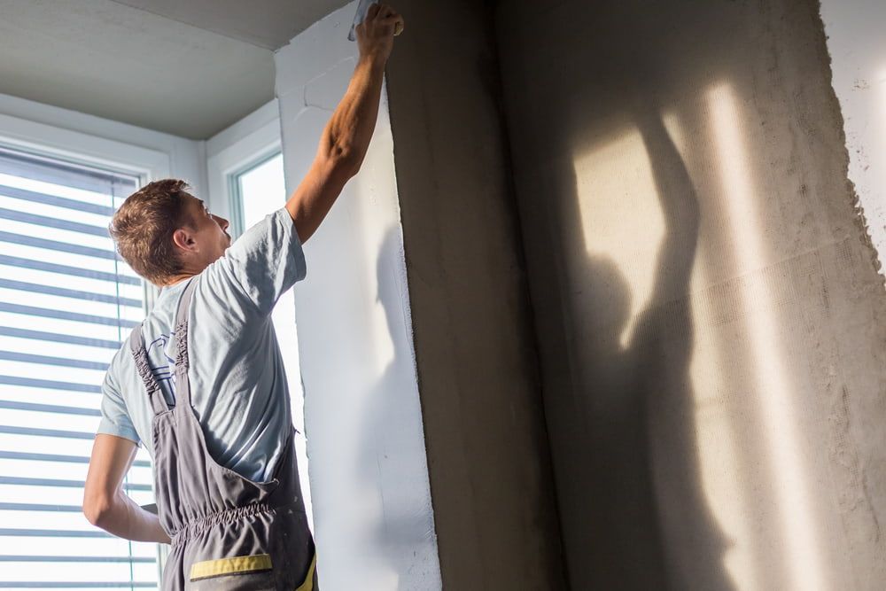 A Man is Hanging Wallpaper on a Wall in a Room — Poljak Plasterers in West End, QLD