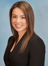 A woman in a black suit is smiling for the camera.