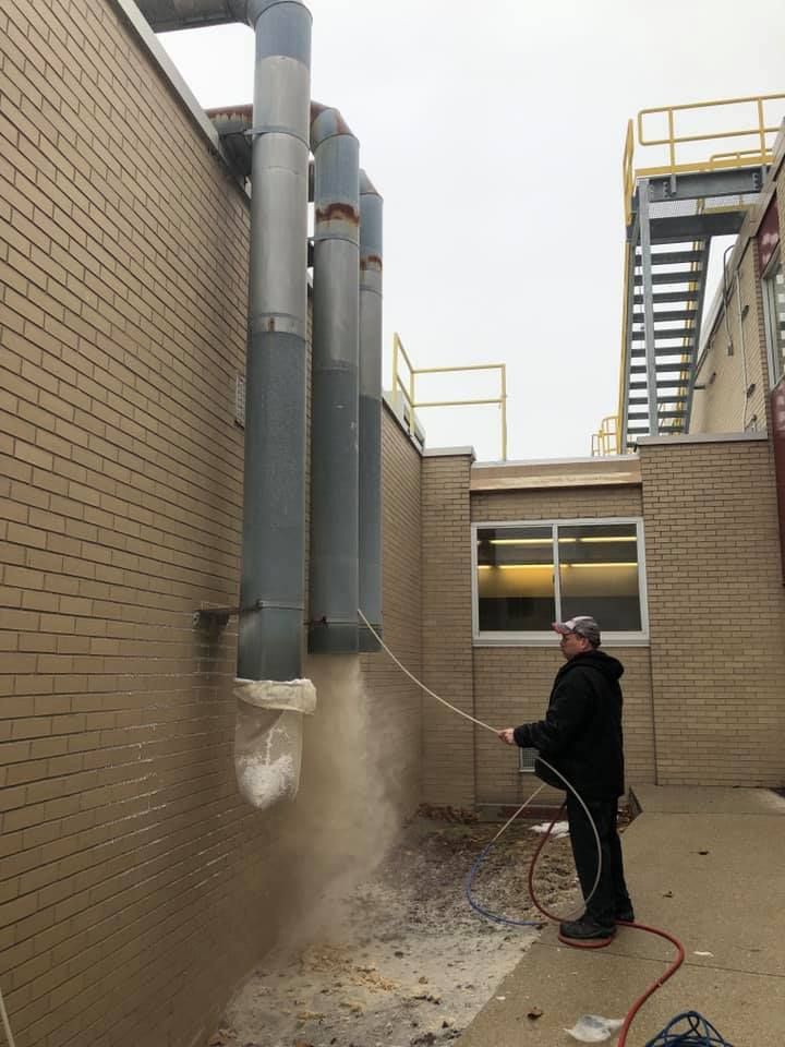 A man is spraying a brick wall with a hose.