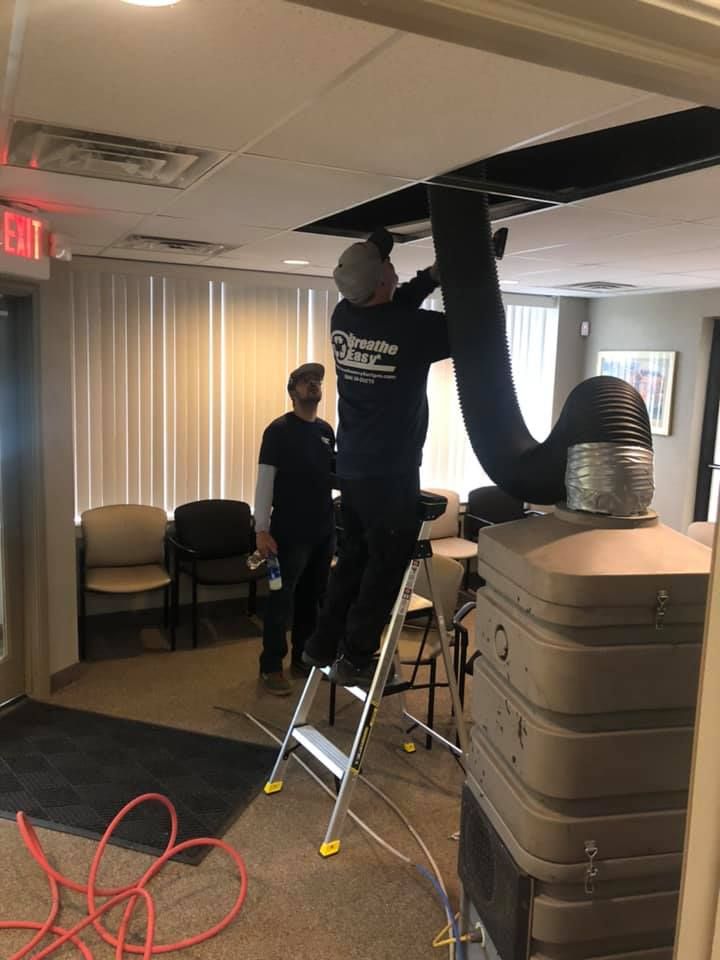 A man is standing on a ladder working on a ceiling fan.