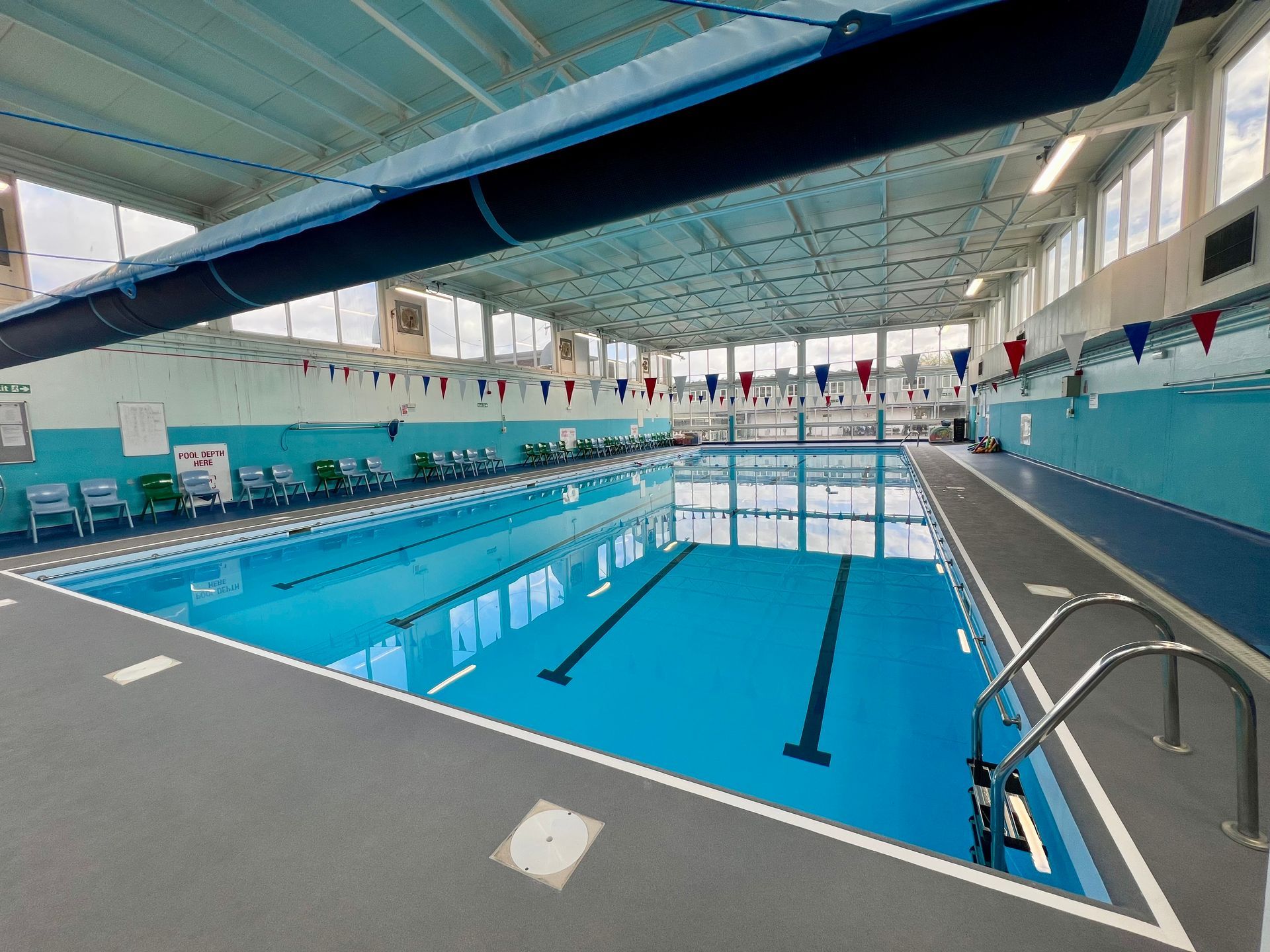 Indoor swimming pool with blue lanes, white walls, and diving boards under a high arched ceiling