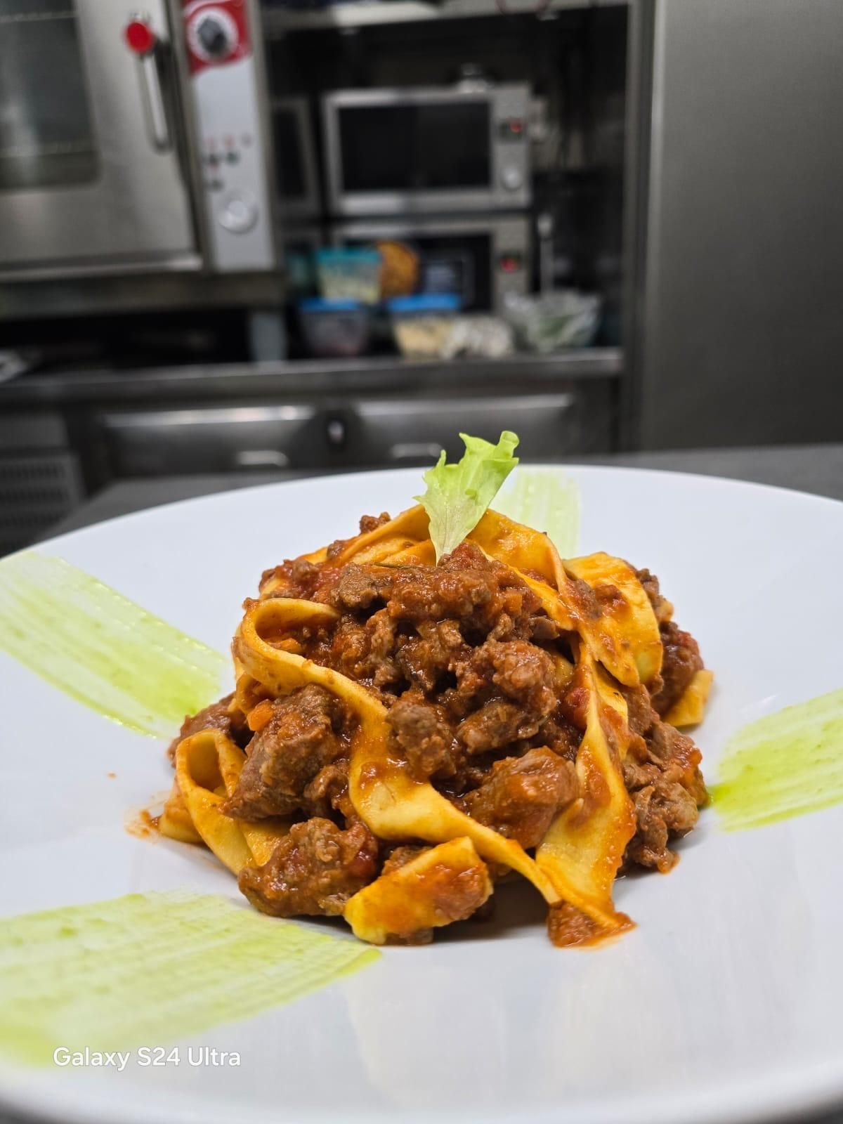 Pasta al ragù, guarnita con lattuga su un piatto bianco, in cucina.