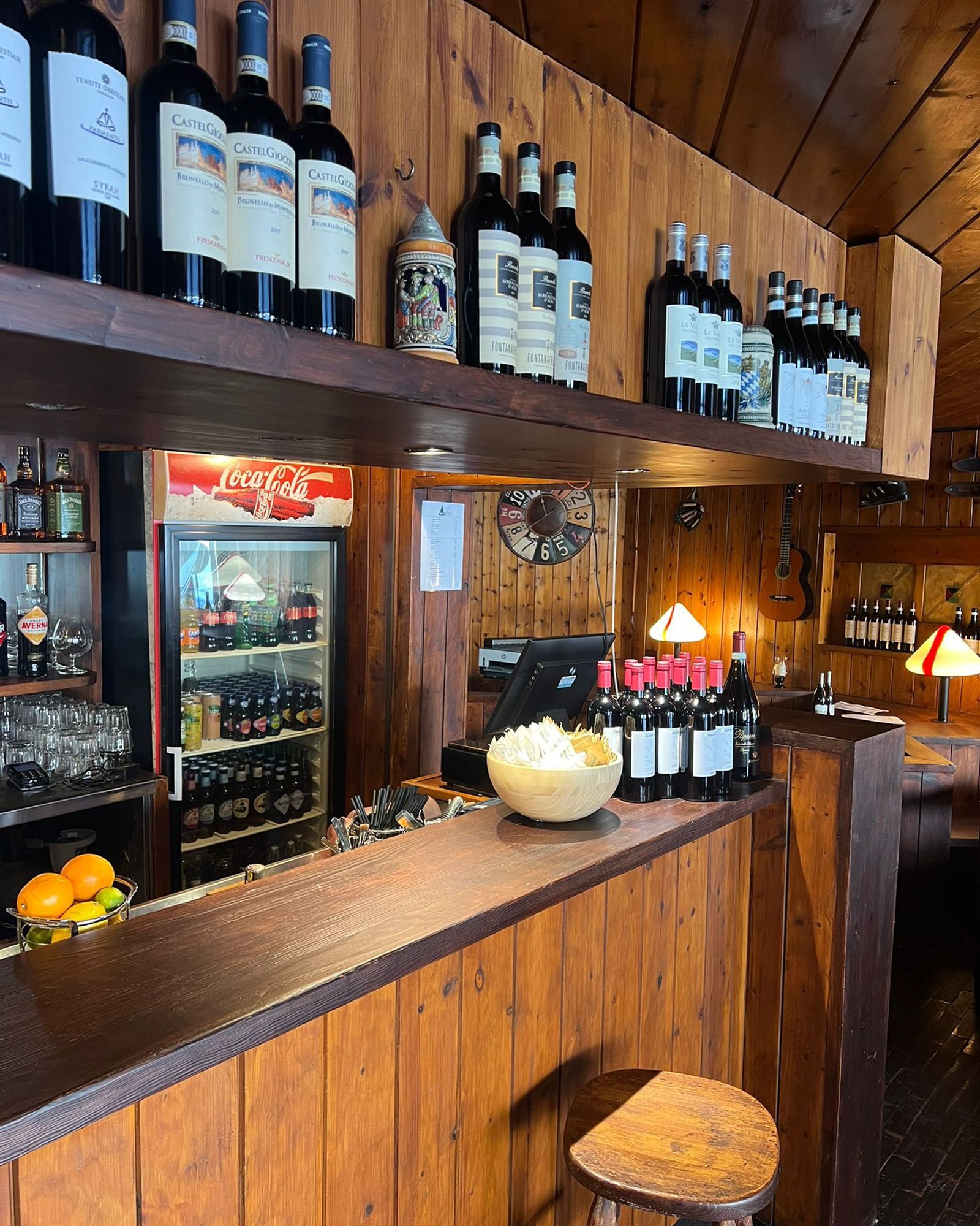 Un'area bar rustica con pannelli in legno, bottiglie di vino, popcorn e un refrigeratore per bevande.