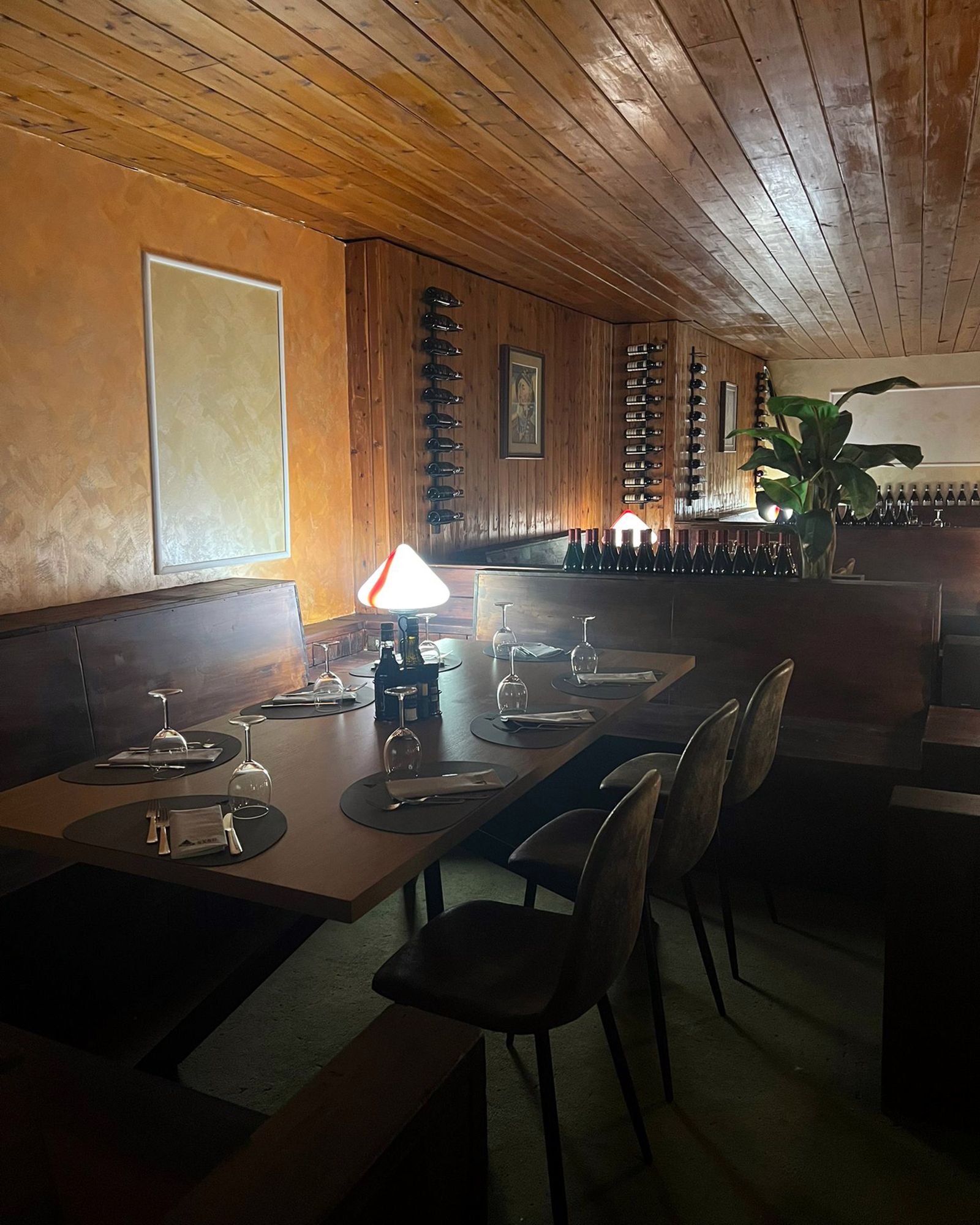 Sala da pranzo con pareti in legno, portabottiglie e tavolo apparecchiato per i pasti.