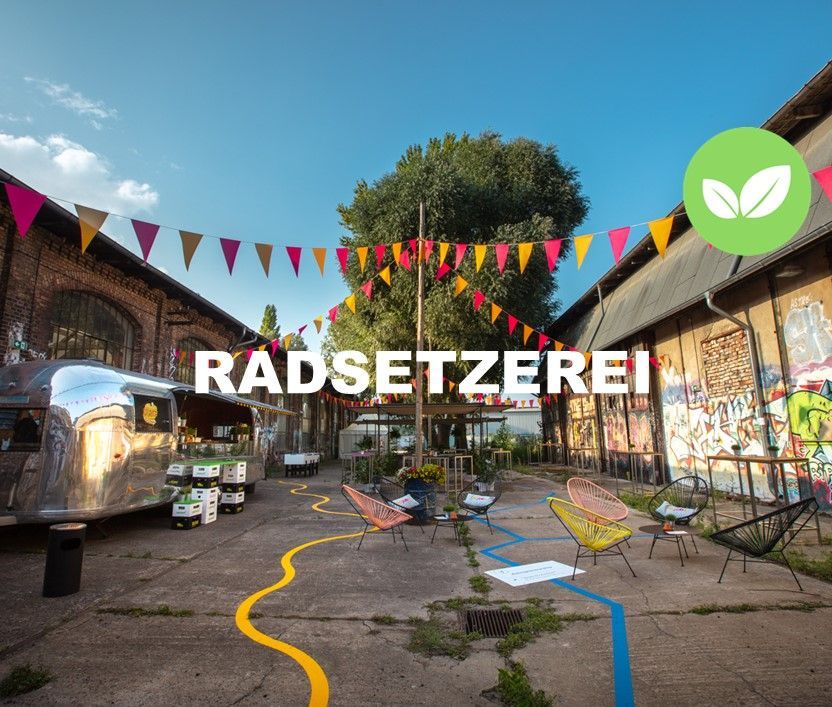 Location Radsetzerei. Blick auf Straße mit Foodtruck, Stühlen und Wimpeln über die Straße