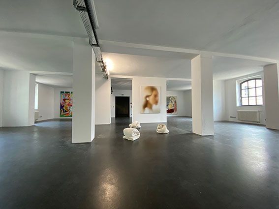 Raum:schwarzer Boden, weiße Säulen und Decke, Industrie-Architektur. Kunst an der Wand, gefaltete Handtücher in der Mitte