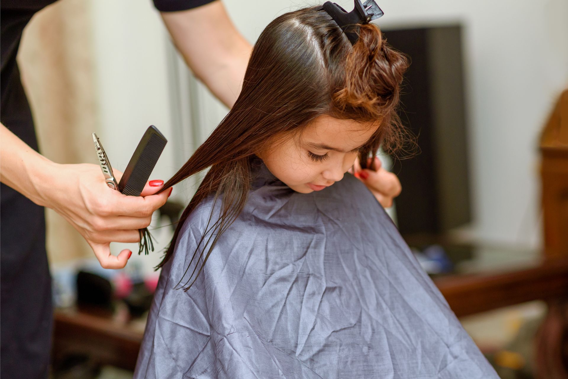 Hairdresser Trimming a Child’s Long Brown Hair With Scissors and Comb — Miilan Hair in Darwin City, NT