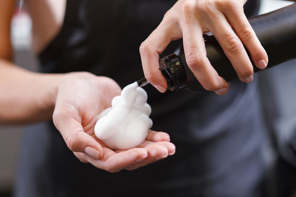 Hands Dispensing White Foam SOAP Into Another Person's Cupped Hand — Miilan Hair in Darwin City, NT