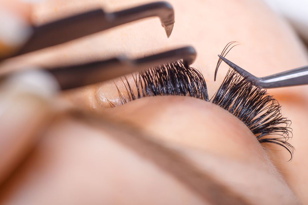Close-up of Tweezers Applying False Eyelashes to a Closed Eye — Miilan Hair in Darwin City, NT