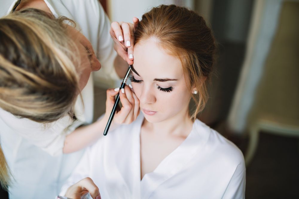Makeup Artist Applying Eyeliner to a Seated Client in a White Robe — Miilan Hair in Darwin City, NT