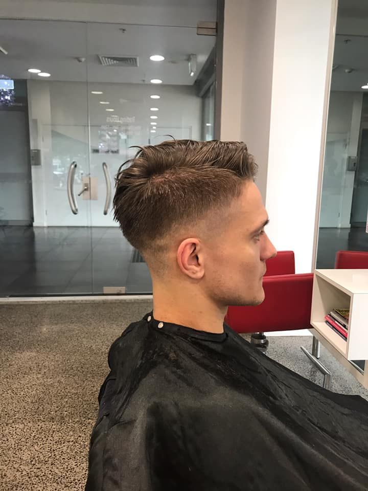 Profile view of a person with a short fade haircut in a barber chair inside a modern salon — Miilan Hair in Darwin City, NT