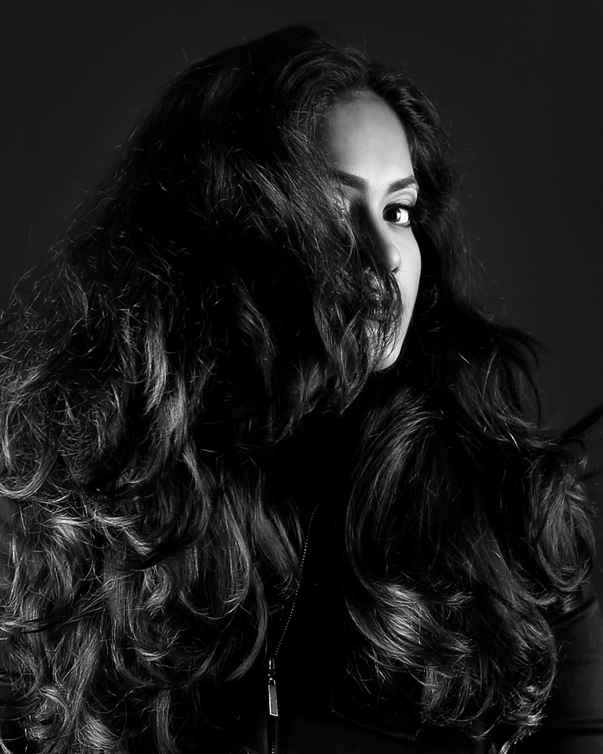 Black-and-white Portrait of a Person With Long Wavy Hair Partially Covering Their Face — Miilan Hair in Darwin City, NT