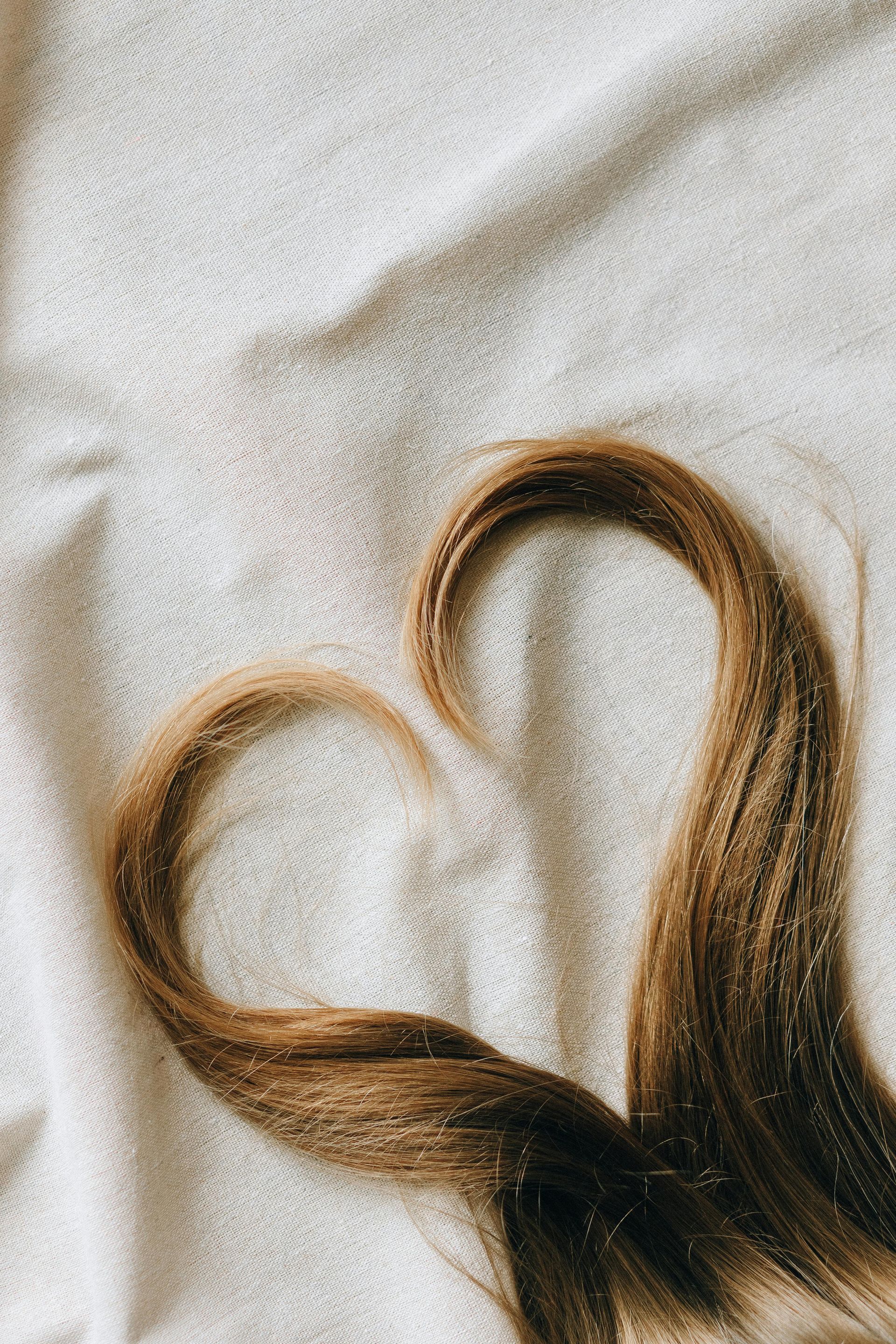 Hair Arranged Into a Heart Shape on a White Textured Background — Miilan Hair in Darwin City, NT