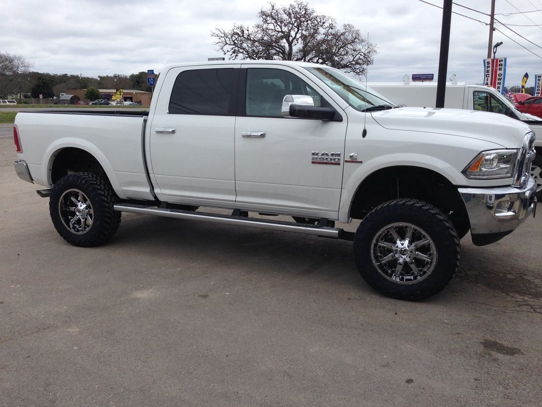A white ram truck is parked on the side of the road.