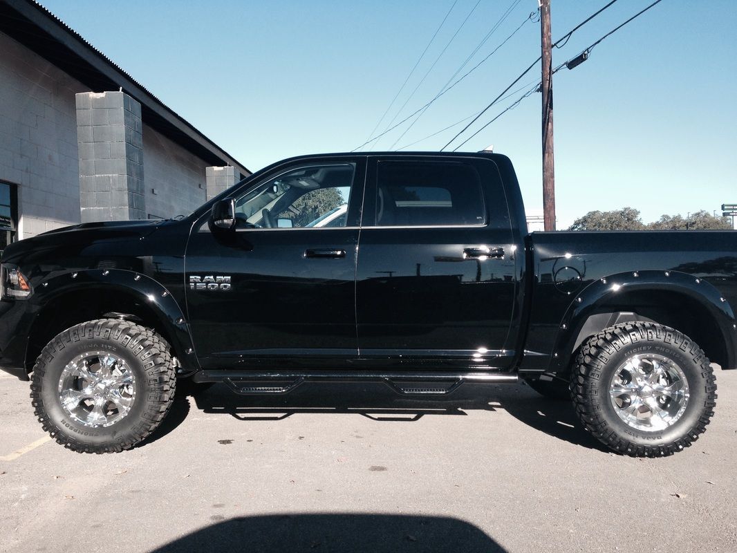 A black dodge ram truck is parked in front of a building