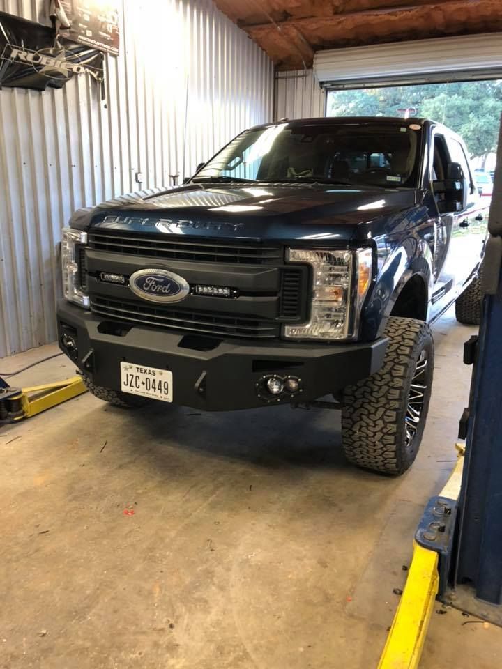 A ford truck is parked in a garage on a lift.
