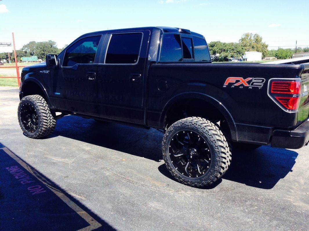 A black ford f150 truck is parked in a parking lot