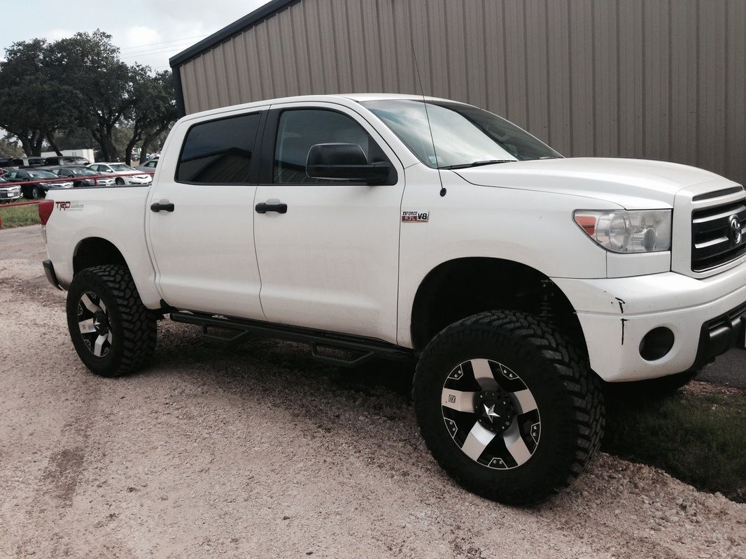 A white truck is parked in front of a building