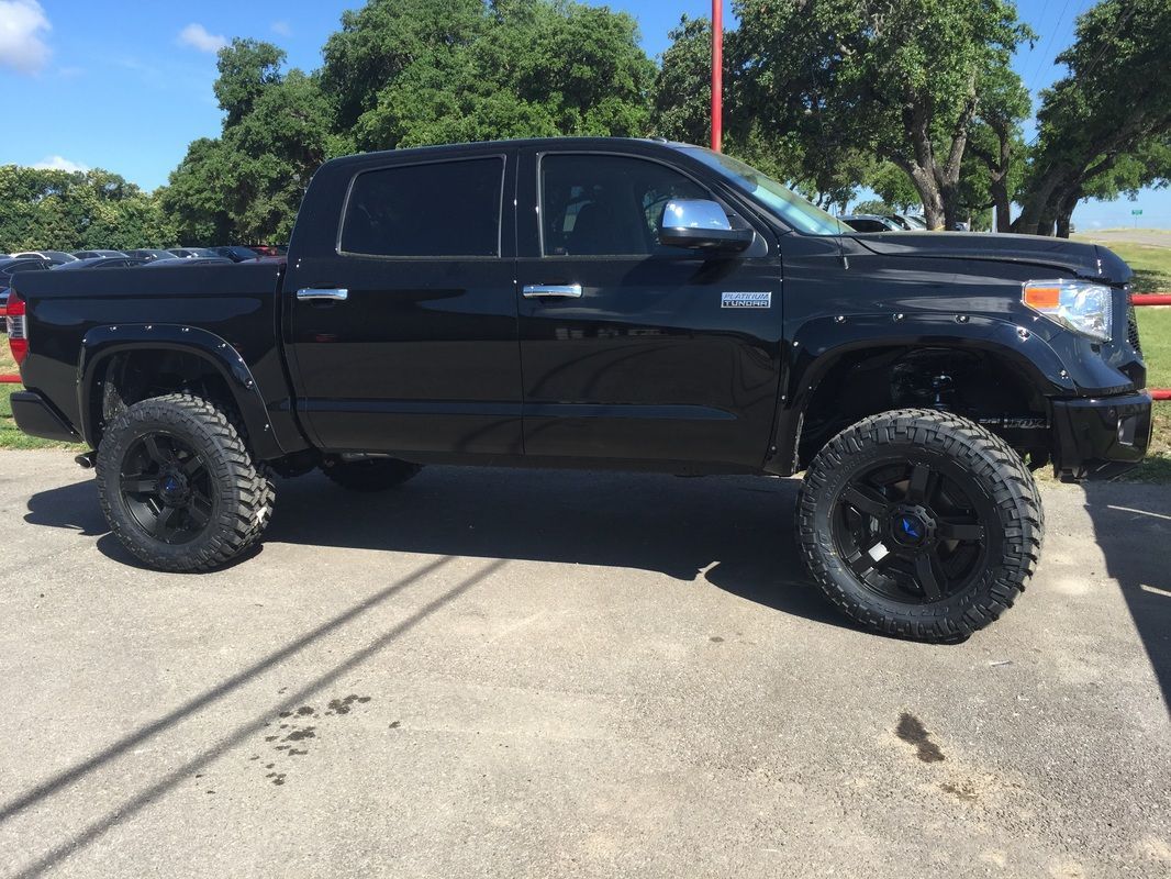 A black truck is parked on the side of the road.
