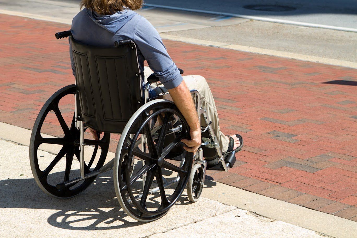 A person in a wheelchair is sitting on a sidewalk.