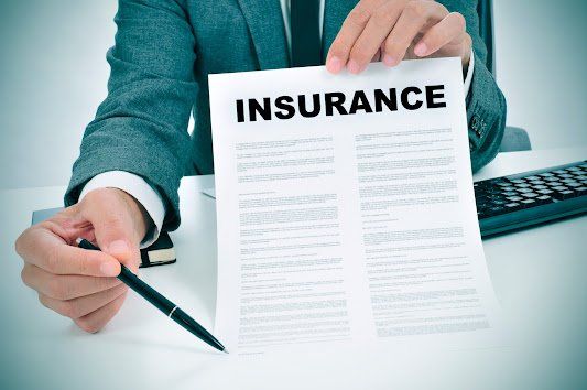 A man is holding a piece of paper with the word insurance on it.
