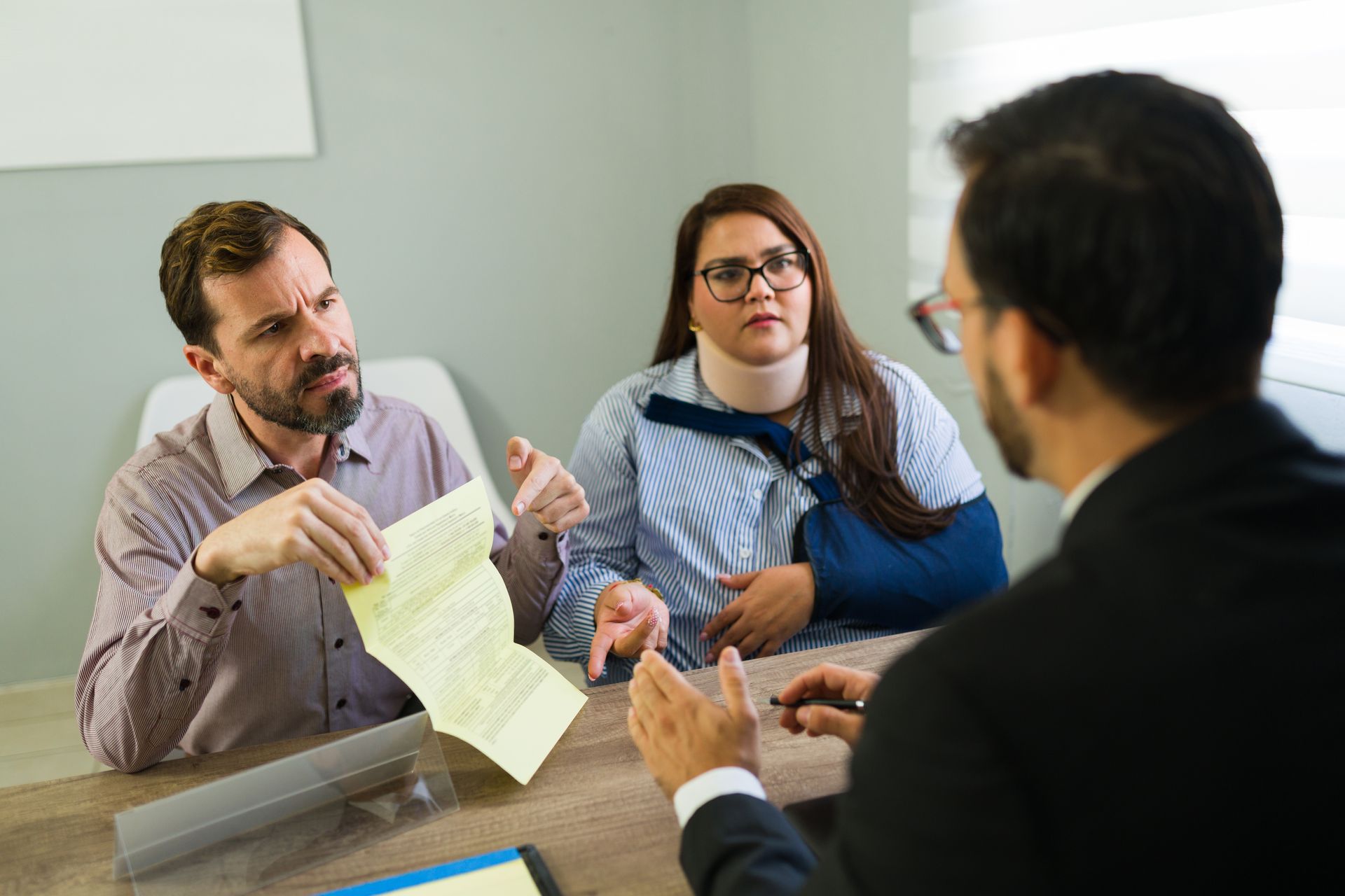 personal injury attorney consulting injured couple reviewing legal documents in office. personal injury attorney consulting injured couple reviewing legal documents in office.