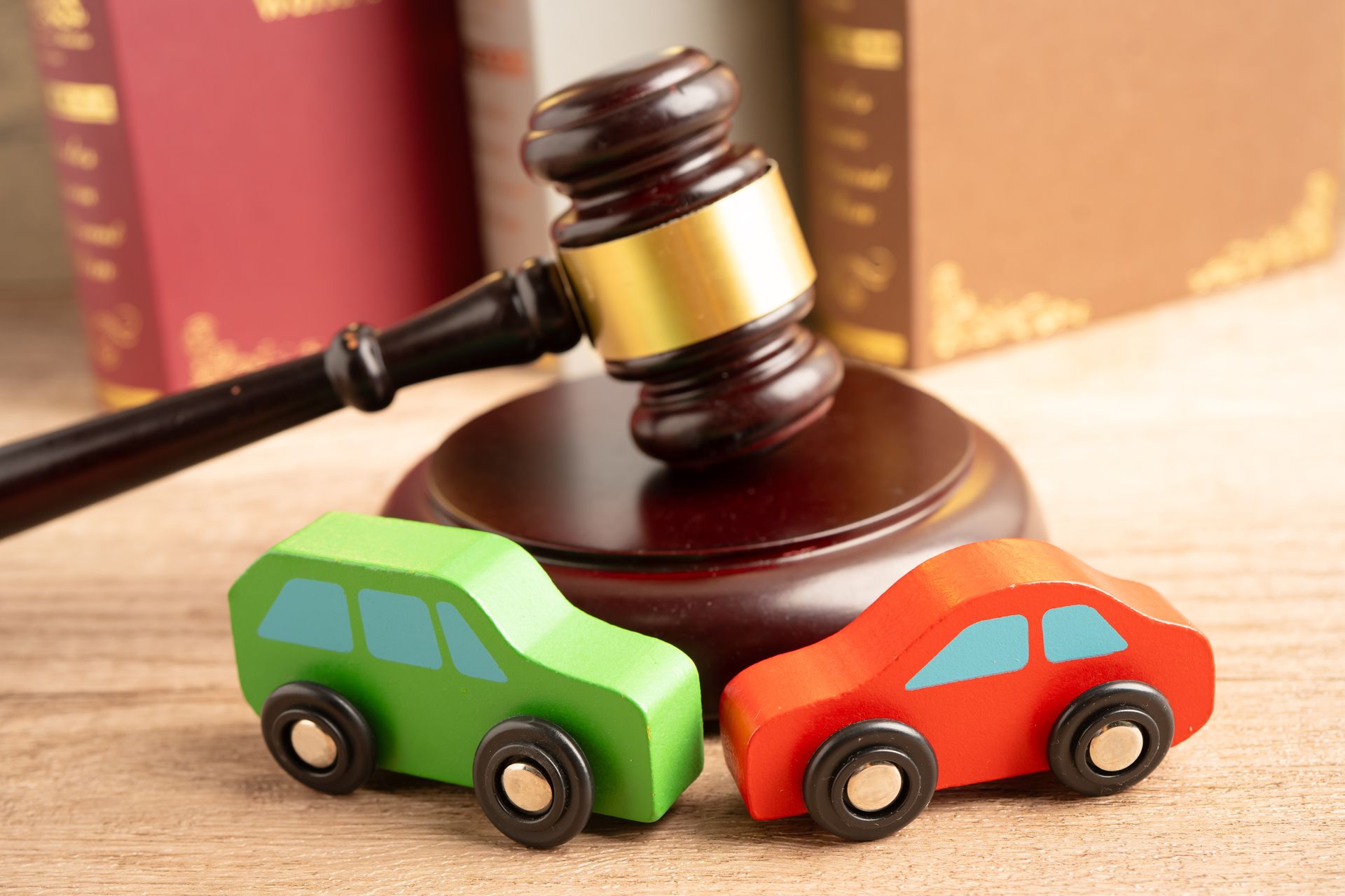 Car accident attorney concept with wooden toy cars beside a judge’s gavel and law books. Car accident attorney concept with wooden toy cars beside a judge’s gavel and law books.