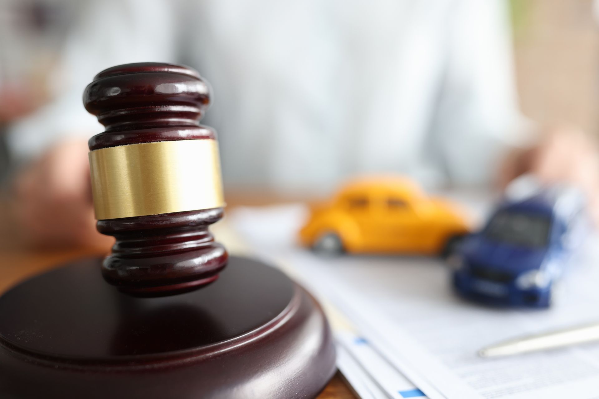 Judge’s gavel beside toy cars symbolizing a legal case involving a vehicle accident. Judge’s gavel beside toy cars symbolizing a legal case involving a vehicle accident.
