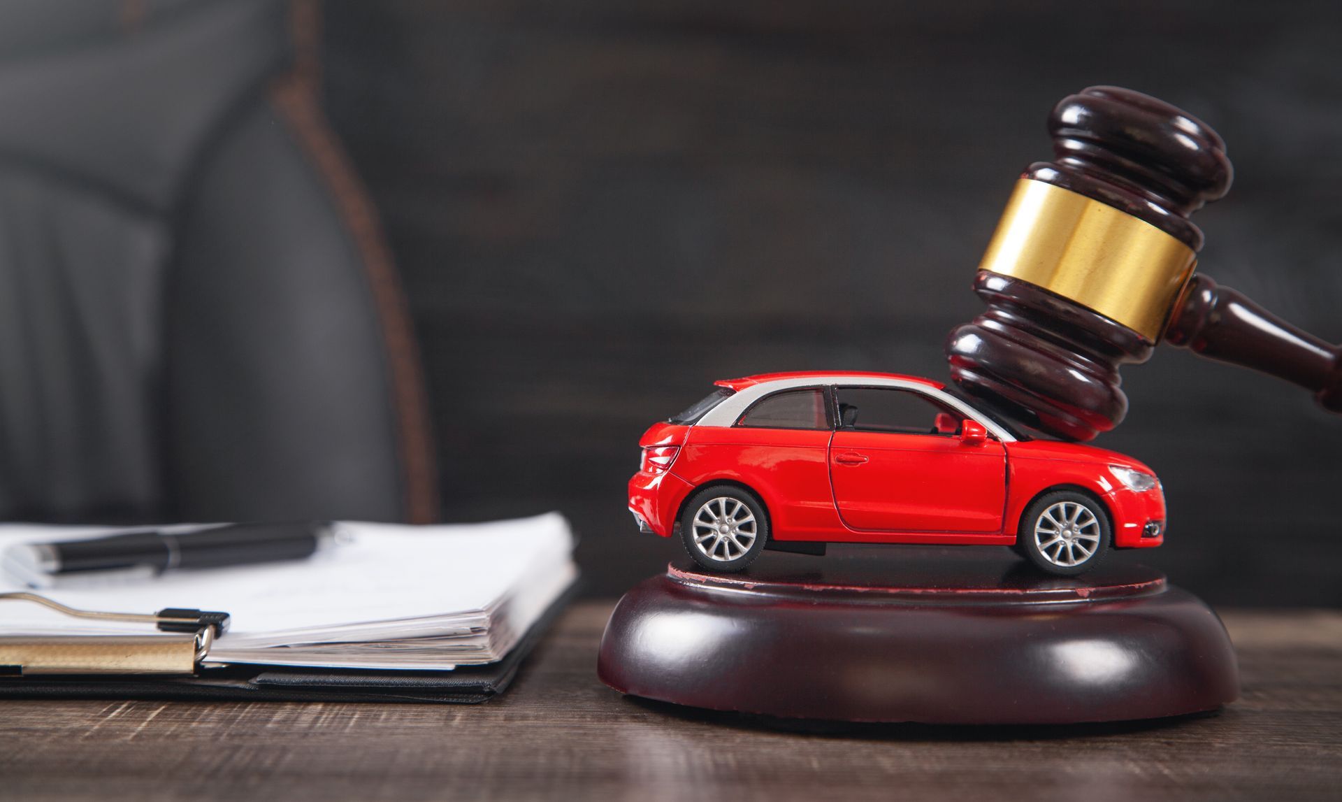 A gavel striking beside a red toy car on a desk symbolizes a car accident case and legal action. A gavel striking beside a red toy car on a desk symbolizes a car accident case and legal action.